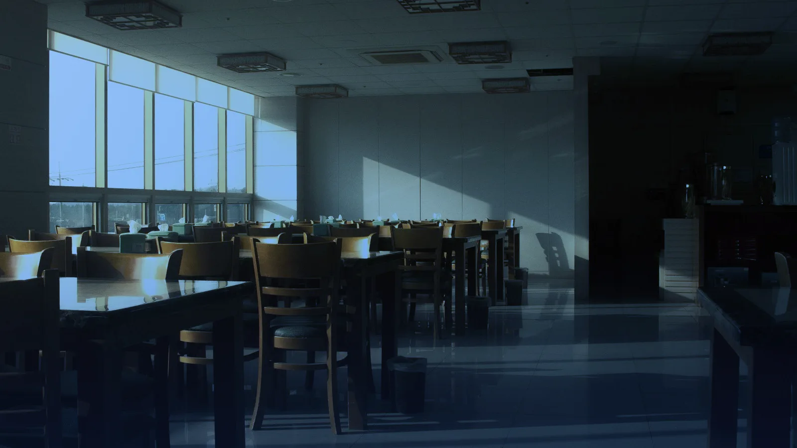 Salón de restaurante vacío con mesas de madera y luz natural