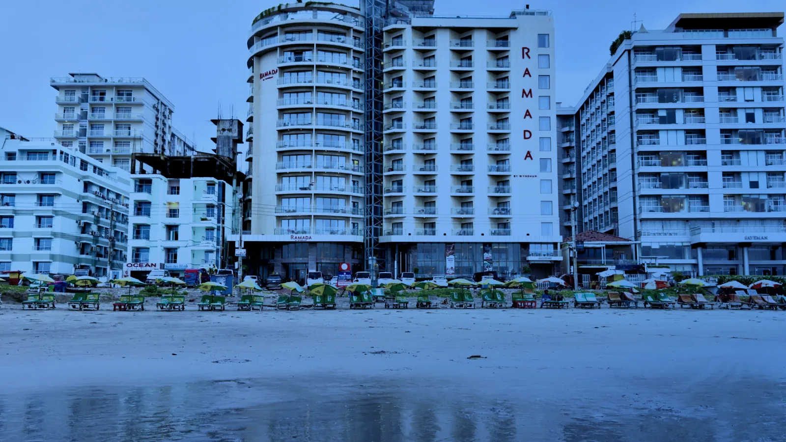 Hoteles frente a una playa con su reflejo en la arena mojada