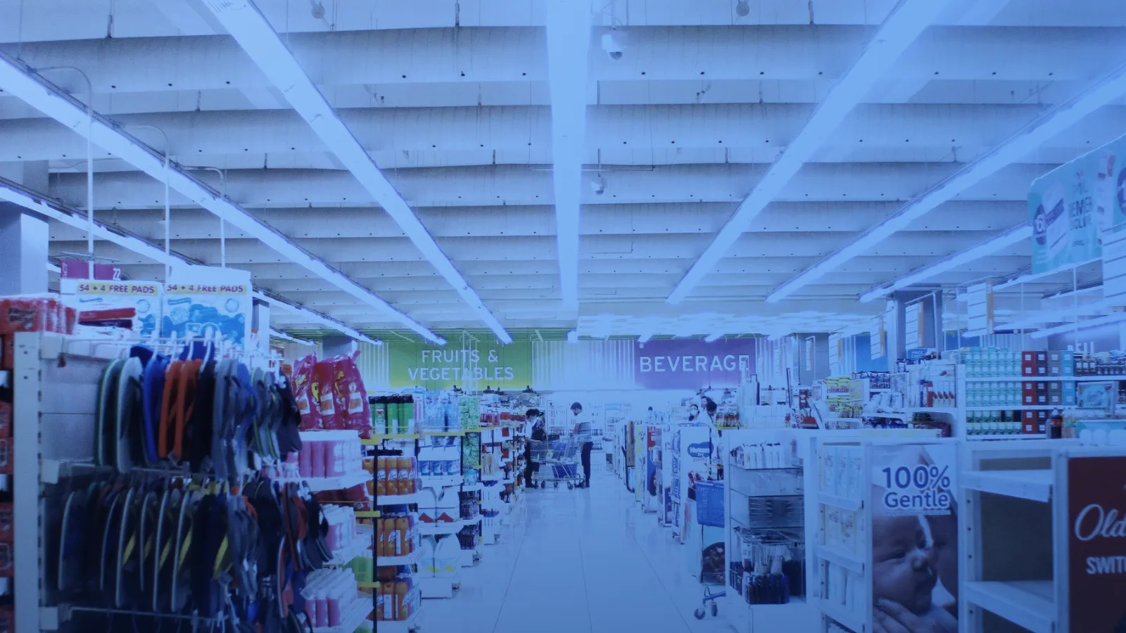 Pasillo amplio de un supermercado con estantes y luces de techo