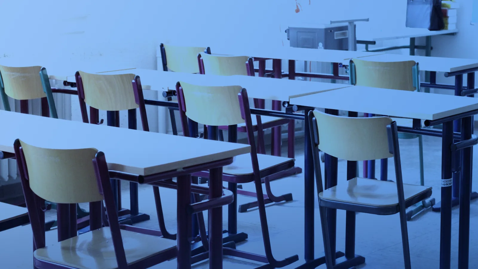 Aula luminosa y vacía con mesas y sillas de madera en filas