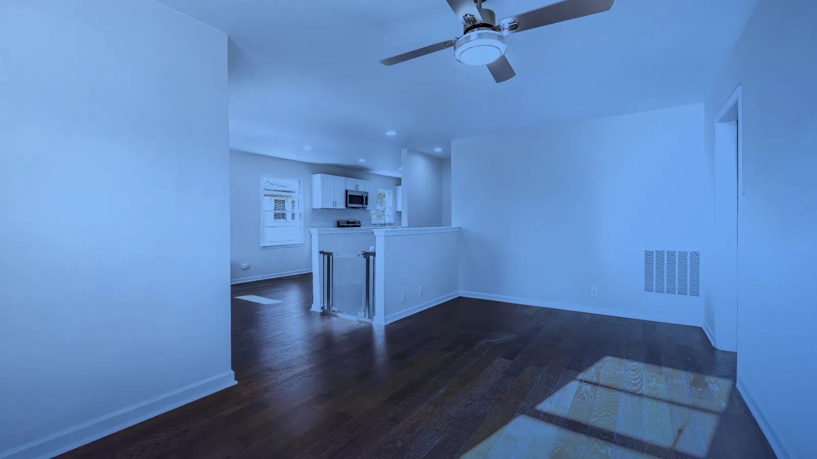 Sala de un apartamento vacío con piso de madera y ventilador de techo