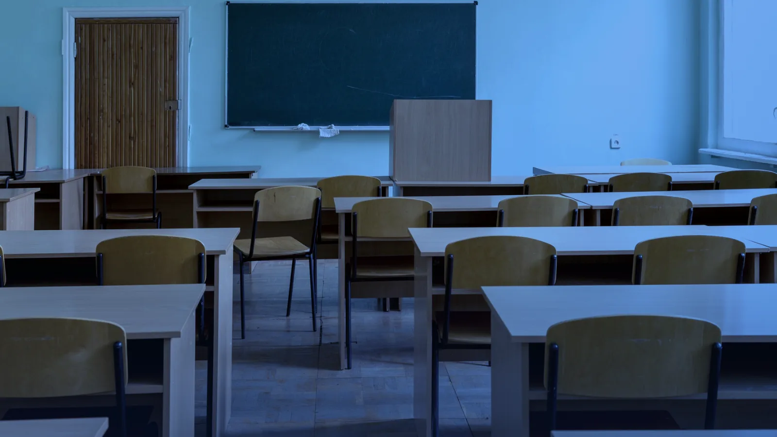Aula vacía con pupitres de madera y una pizarra verde