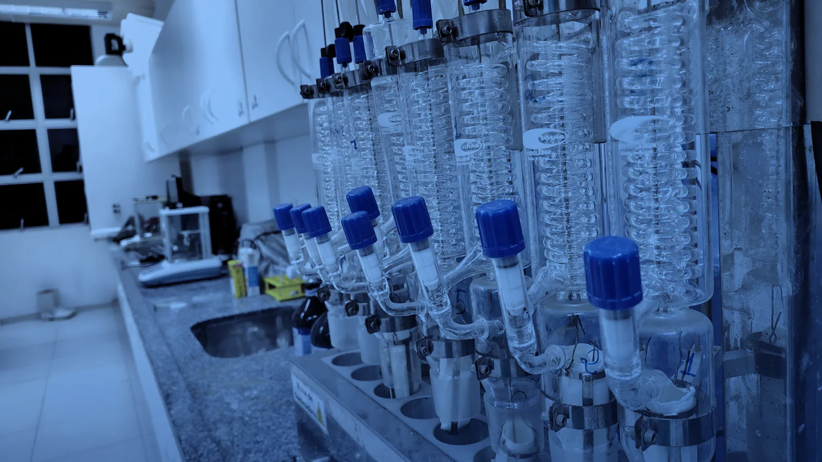 Laboratorio con condensadores de vidrio sobre un mesón de trabajo