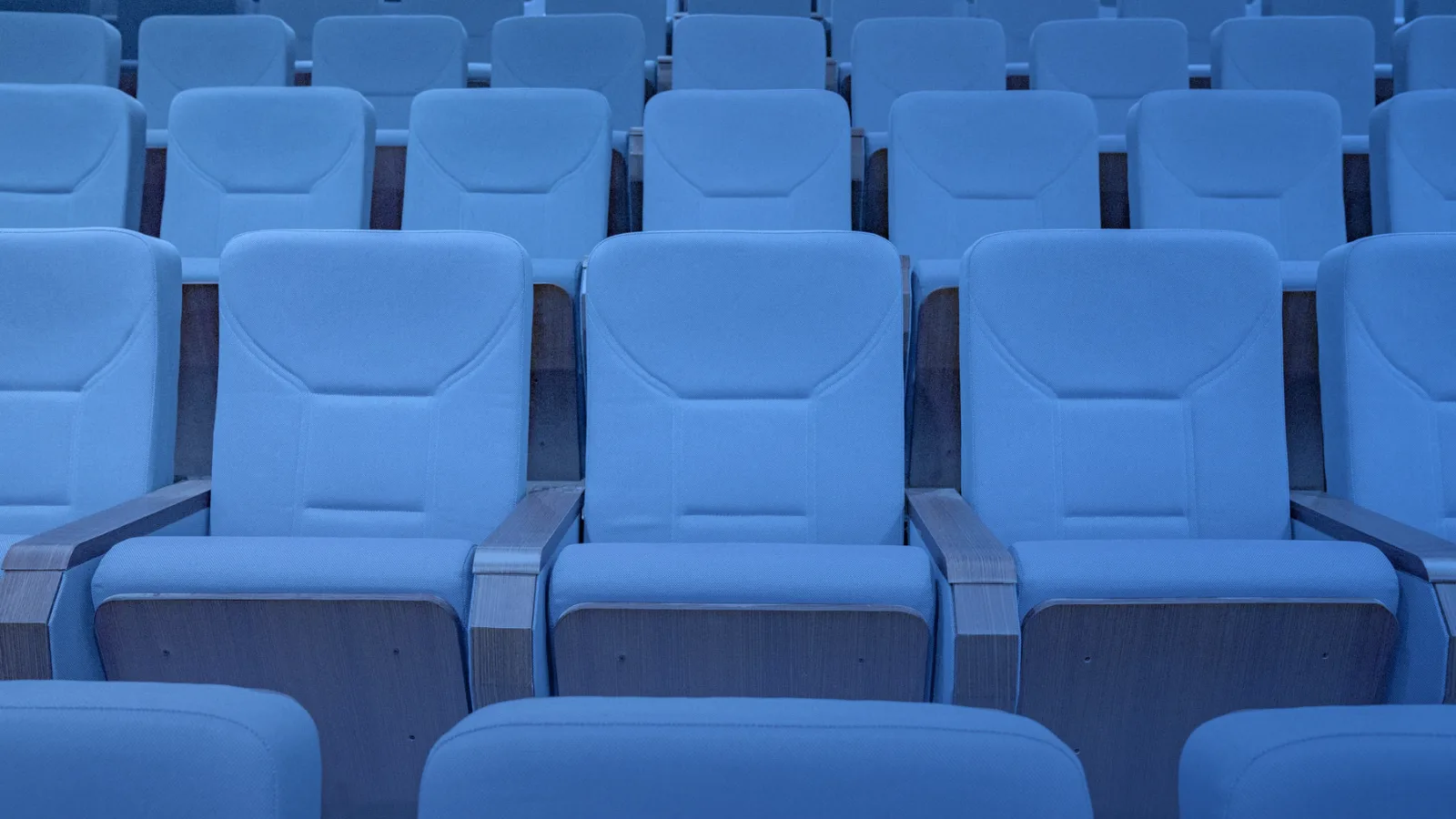 Filas de butacas azules en un auditorio vacío