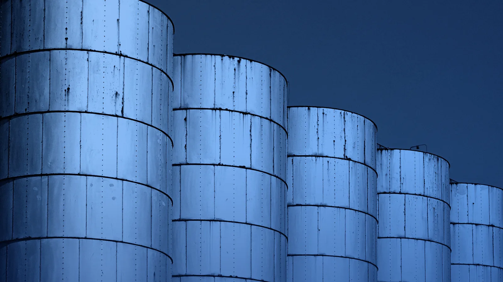 Fila de silos metálicos industriales bajo un cielo despejado