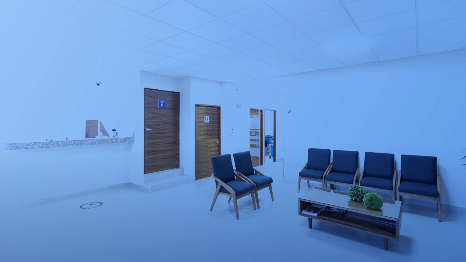 Sala de espera médica luminosa con sillas azules y recepción